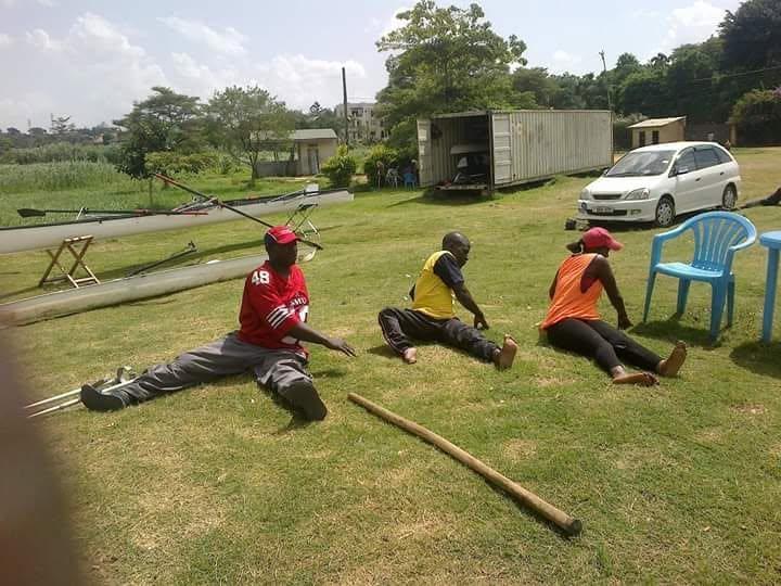 Participants sit together on the grass with oars during a training session.
