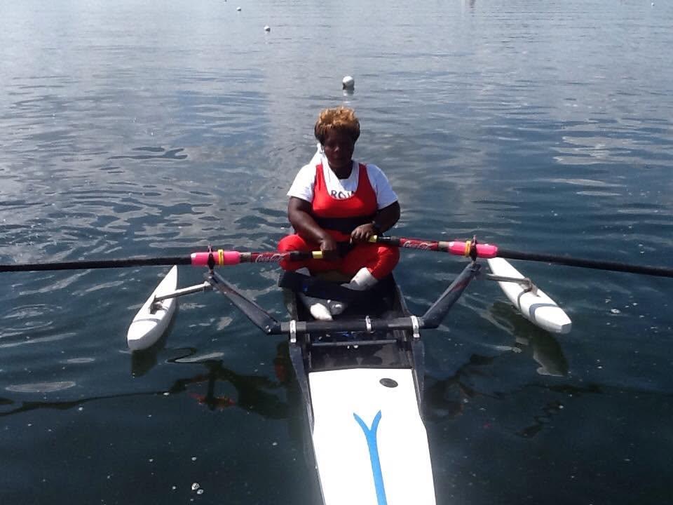An athlete rows an adapted boat fitted with stabilising pontoons, facing the camera.
