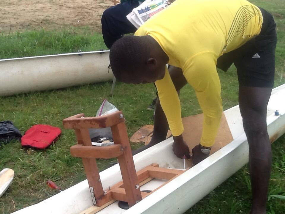 An athlete adjusts an oarlock while preparing a boat.