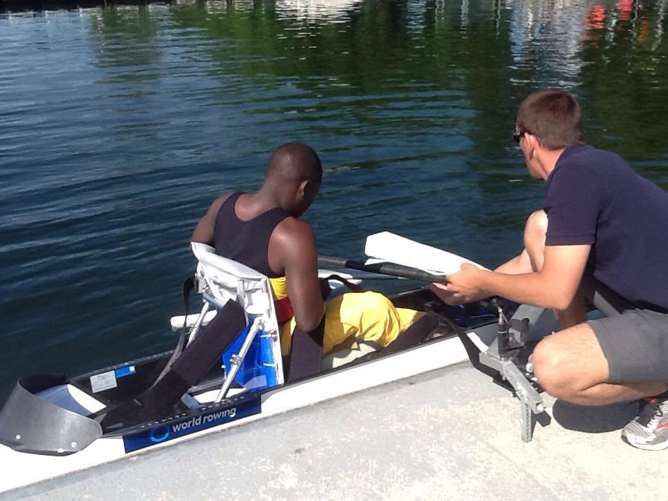 Athletes prepare a boat at the lakeside, surrounded by water hyacinth.