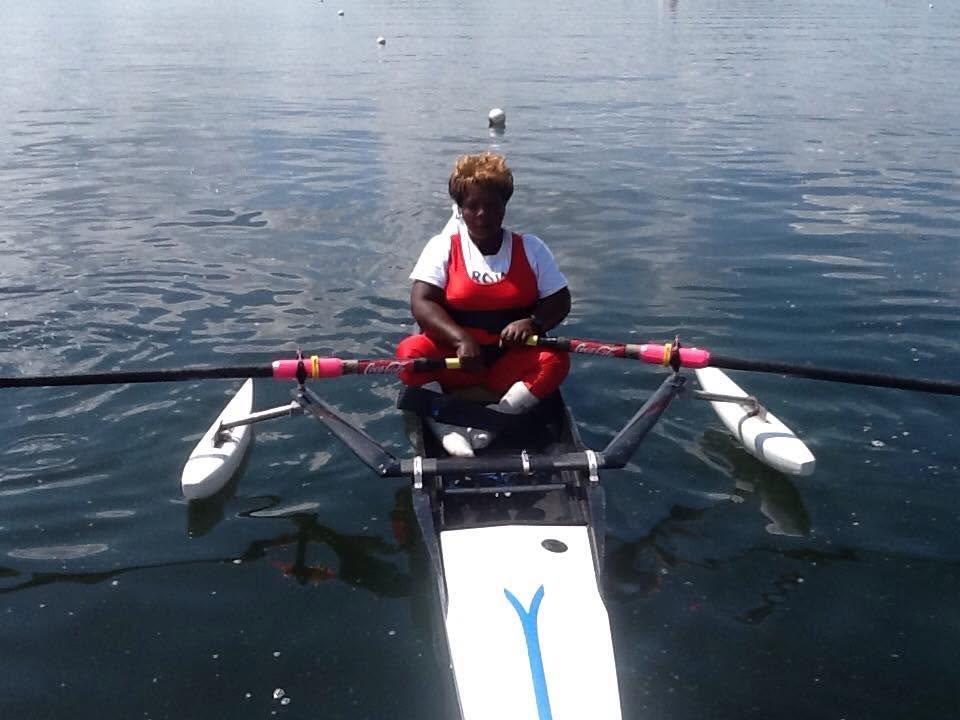 A Para rowing athlete racing in an adapted single scull fitted with stabilising pontoons.