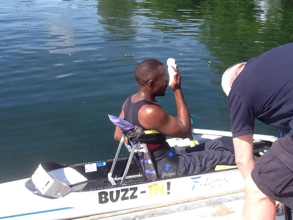 An athlete seated in an adapted single scull fitted with stabilising pontoons at the dock.